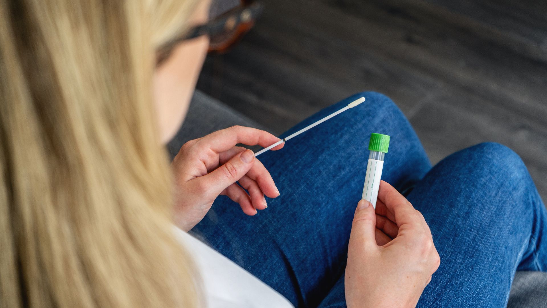 A woman holds a swab after determining the differences between PCR vs Rapid Antigen COVID Tests